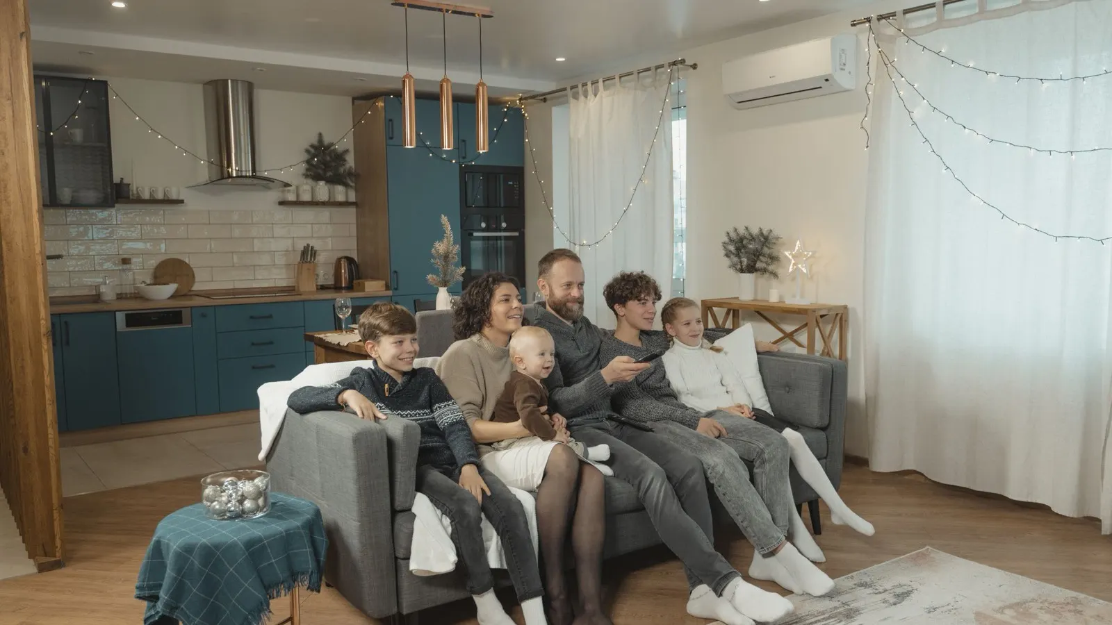 Best DIY mini split heat pump 2026 — a family on the sofa in a warm open-plan living room in winter, with a ductless wall-mounted mini split heat pump above the window