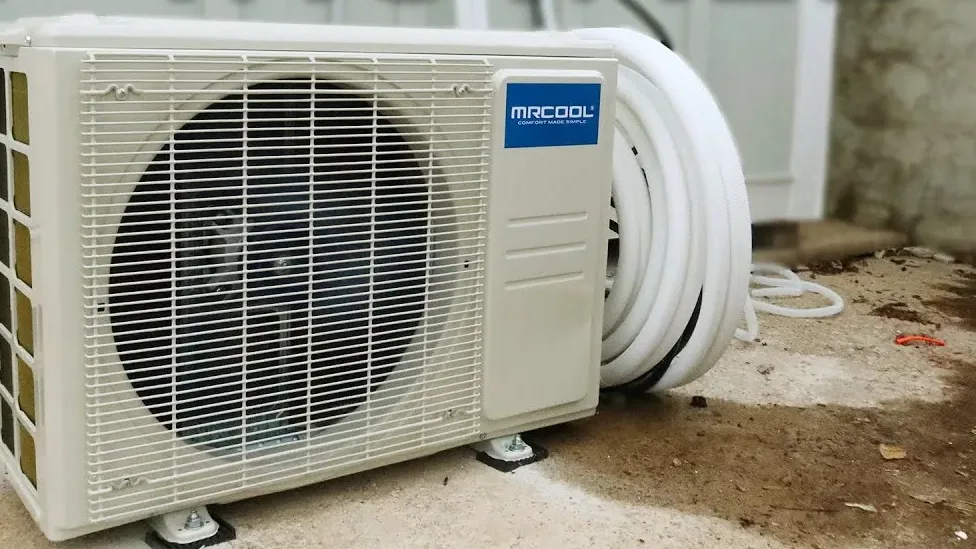 Best DIY mini split systems 2026 — a MRCOOL DIY outdoor condenser with its pre-charged quick-connect line set coiled beside it, the format compared here against Zone Air, Pioneer, Senville, and Cooper & Hunter