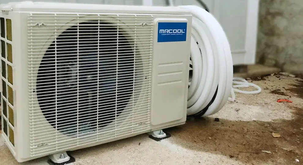 MRCOOL DIY 5th Gen 12000 BTU precharged line set installation: MRCOOL outdoor condenser with the coiled 25 ft pre-charged quick connect line set beside it
