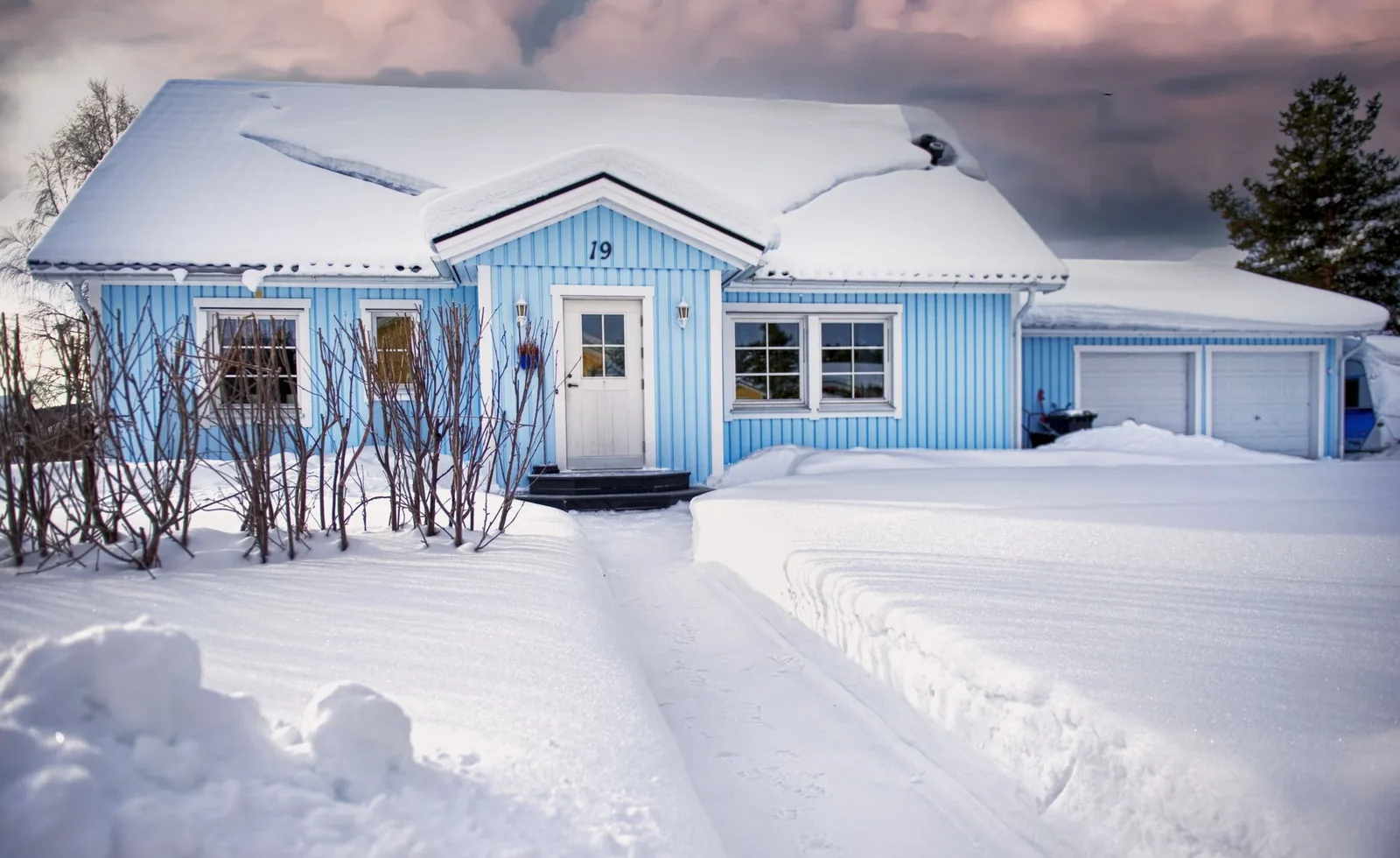 Light blue house with snow-covered roof and cleared path to door number 19, showing quantum hyperformance vs pioneer wys garage setup