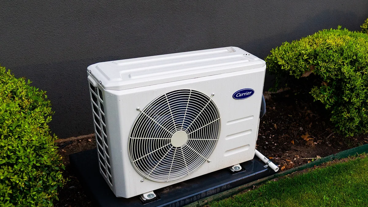 Best DIY mini split brands 2025-2026: an outdoor split-system heat pump condenser mounted beside a house